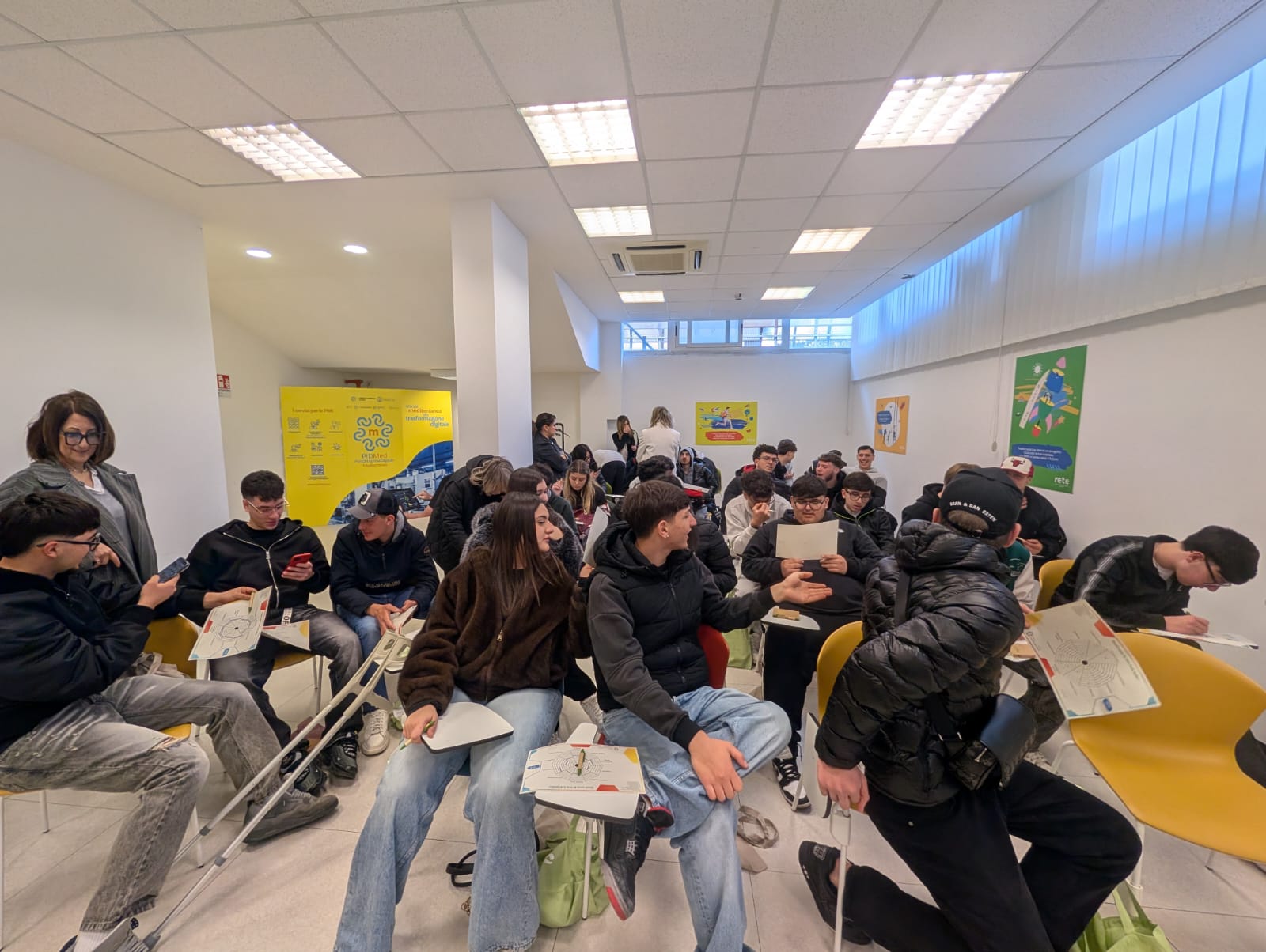 Dettaglio di studenti dell'Istituto ProfAgri di Salerno che compilano a penna il modulo 'Radar delle Competenze' durante un laboratorio pratico dell'Hackathon, seduti in cerchio per favorire il confronto.
